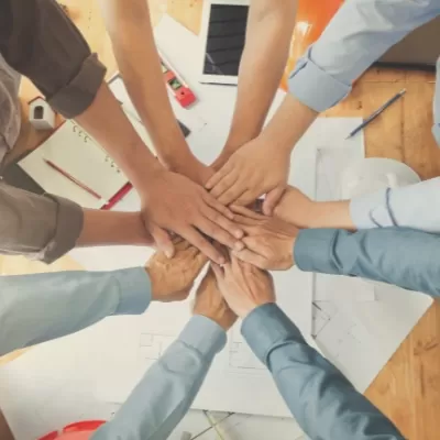 Office workers putting their hands together in a circle to signify teamwork