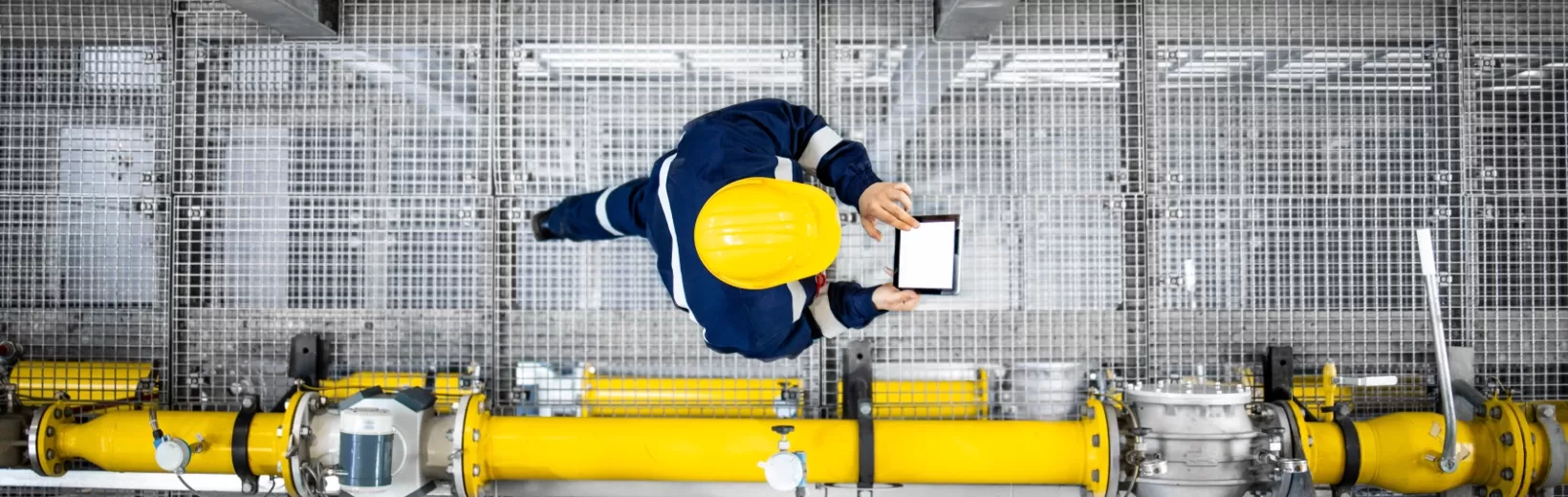 Aerial photo of factory worker crossing gantry with tablet
